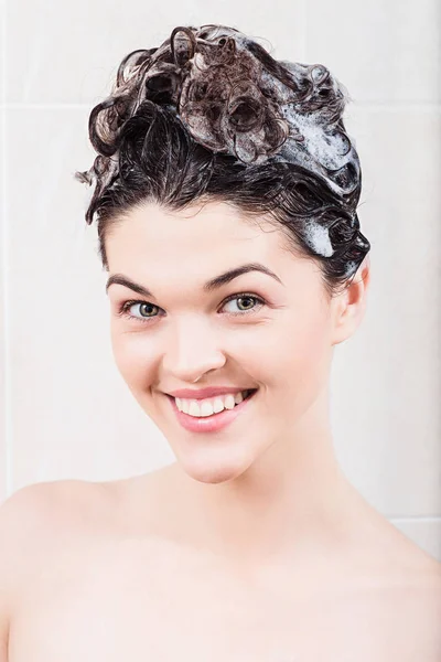 Giovane donna che lava i capelli con shampoo sotto la doccia — Foto Stock