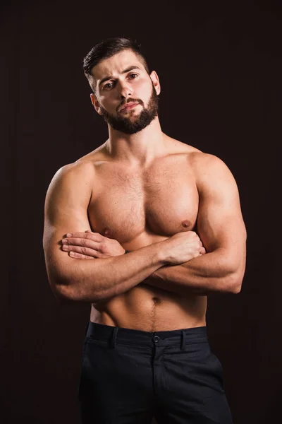 Young handsome muscular man with a beard, posing on a black back — Stock Photo, Image