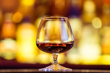 Parlak ışıklar bir arka plan üzerine bir bardak konyak. Geleneksel 