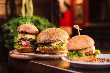 Karanlık bir arka plan üzerinde beyaz tabakta üç sulu lezzetli burger