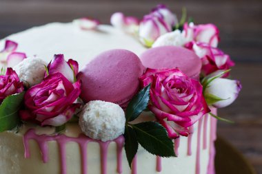 Ahşap arka plan üzerinde gül dekorasyonu ile beyaz pasta