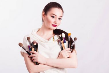 Beyaz arka planda elinde fırçayla makyaj sanatçısı.