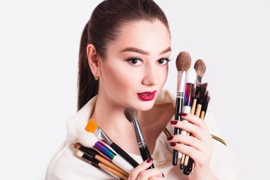 Beyaz arka planda elinde fırçayla makyaj sanatçısı.