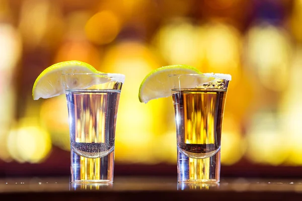 Tequila de plata y oro en un vaso sobre un fondo de labio brillante — Foto de Stock