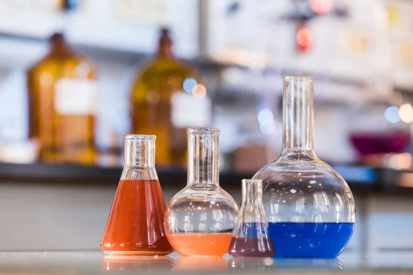 Kádinka s barevnými tekutinami v laboratoři — Stock fotografie