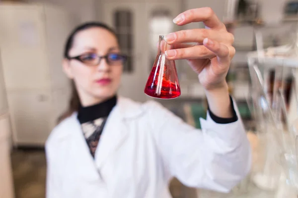 Vaso de precipitados con líquido en manos de mujeres científicas — Foto de Stock