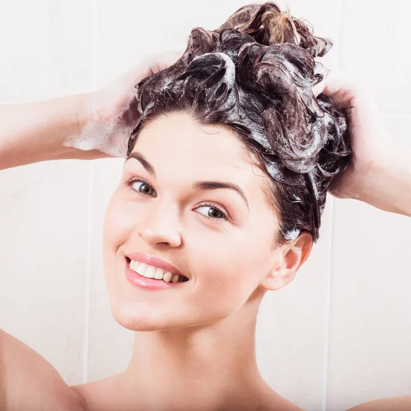 Ung kvinna tvätta håret med schampo i duschen — Stockfoto