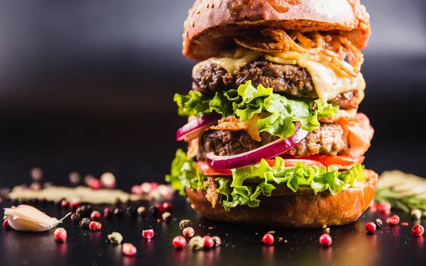 Siyah arka planda baharatlı lezzetli bir burger.