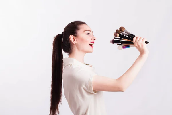 Maquiagem artista segurando escovas para maquiagem como um microfone em um — Fotografia de Stock