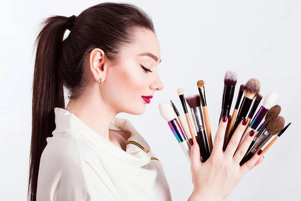 Make-up kunstenaar met penselen in de hand op een witte achtergrond — Stockfoto