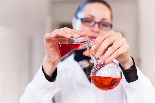 Científica en un laboratorio sosteniendo un frasco con líquido — Foto de Stock