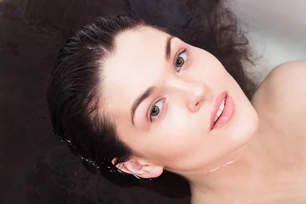 Jonge vrouw in de badkamer te spoelen haar onder water — Stockfoto