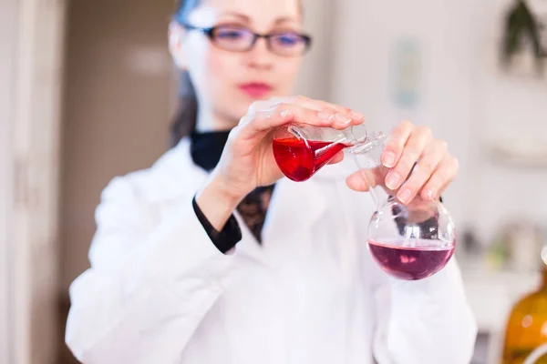 Una joven científica en un laboratorio mezcla reactivos — Foto de Stock