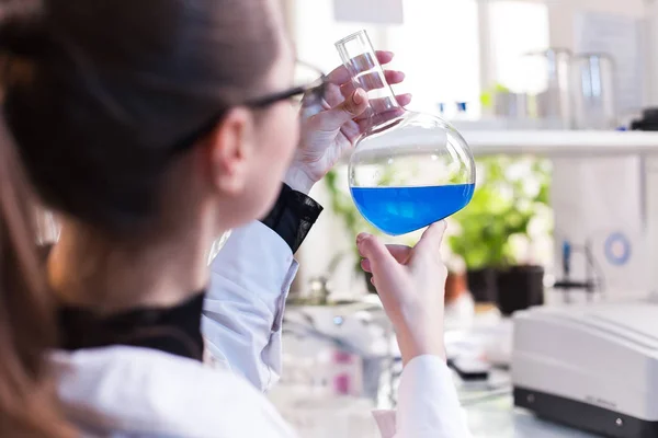 Vaso de precipitados con líquido en manos de mujeres científicas — Foto de Stock