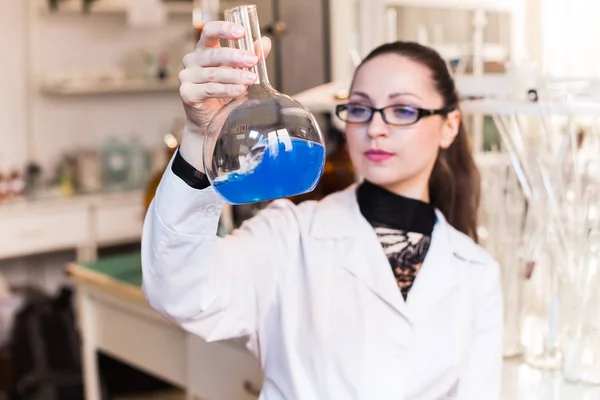 Vaso de precipitados con líquido en manos de mujeres científicas — Foto de Stock
