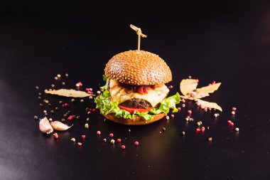 Siyah arka planda baharatlı lezzetli bir burger.