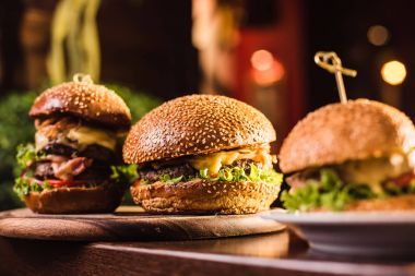 Karanlık bir arka plan üzerinde beyaz tabakta üç sulu lezzetli burger