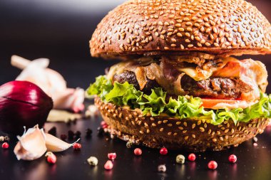 Siyah arka planda baharatlı lezzetli bir burger.