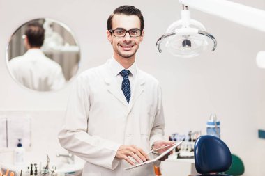 Doktor diş hekimi tablet üzerinde çalışan kabine