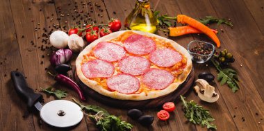 İtalyan pizza malzemelerle koyu ahşap zemin üzerine salam dilimleri ile 