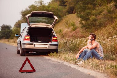 Genç bir adam yolun kenarında oturuyor. Tahliye Servisi çağırır