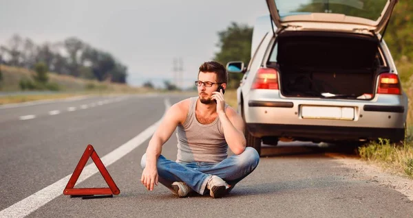 Genç bir adam yolun kenarında oturuyor. Tahliye Servisi çağırır