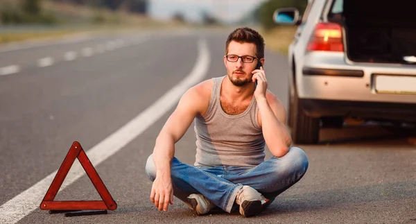 Genç bir adam yolun kenarında oturuyor. Tahliye Servisi çağırır