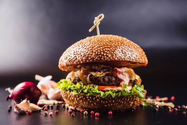 Siyah arka planda baharatlı lezzetli bir burger.