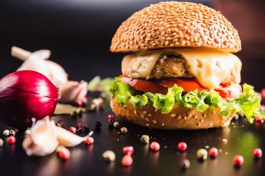 Siyah arka planda baharatlı lezzetli bir burger.