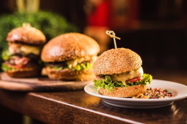 Karanlık bir arka plan üzerinde beyaz tabakta üç sulu lezzetli burger