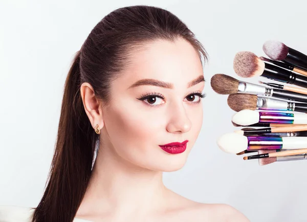 Het gezicht van een mooi meisje en make-up borstel op witte CHTERGRO — Stockfoto