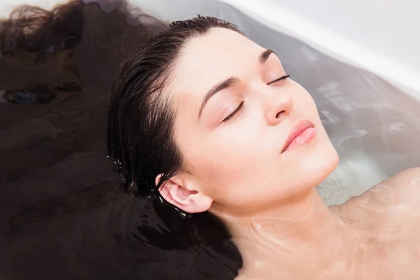 Jeune femme dans la salle de bain pour rincer les cheveux sous l'eau — Photo