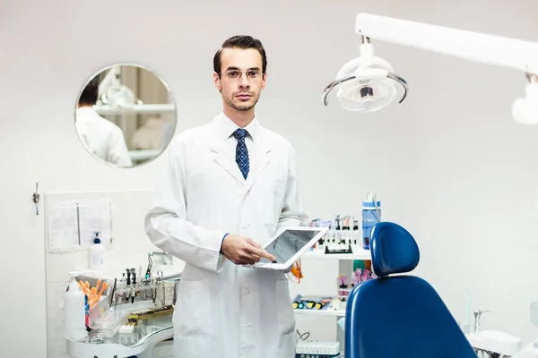 Médico dentista en el gabinete trabajando en la tableta —  Fotos de Stock