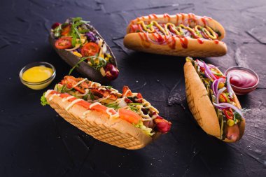 Dört sosisli sandviç (yakın karanlık bir arka plan üzerinde)