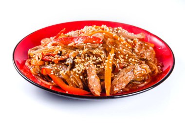 Beyaz zemin üzerine kırmızı bir tabakta sığır, biber ve susam tohumu ile erişte. Geleneksel İtalyan makarna. Kapat