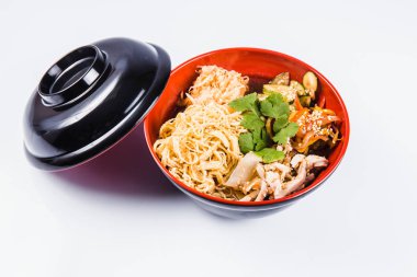 Erişte (tavuk, biber, salatalık ve susam tohumu) beyaz zemin üzerine kırmızı bir tabakta karıştırın. Geleneksel İtalyan makarna. Kapat