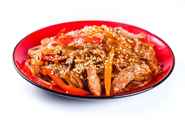 Noodles with  beef, pepper and sesame seeds on a red plate on a white background. Traditional Italian pasta. Close