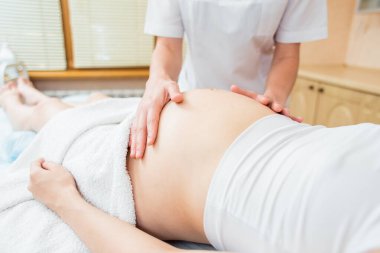Yakın bir masaj eller hamile bir kız bir kozmetik odada göbek hafif bir masaj terapisti yapar