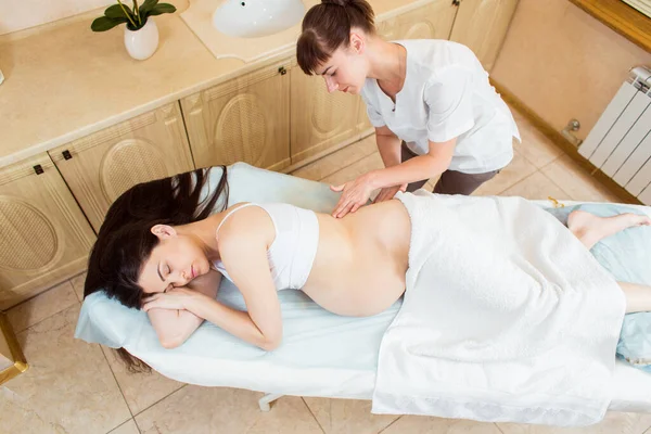 美丽的黑发孕妇在美容师的房间里享受着背部按摩 — 图库照片