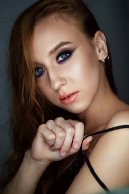 Karanlık bir arka planda güzel bir akşam makyajı olan genç bir kadının portresi.