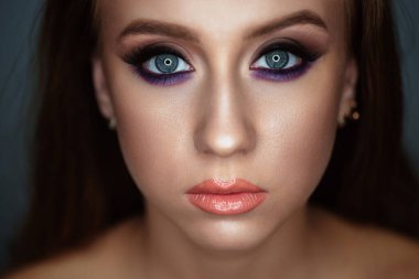 Karanlık bir arka planda güzel bir akşam makyajı olan genç bir kadının portresi.