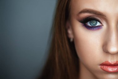 Karanlık bir arka planda güzel bir akşam makyajı olan genç bir kadının portresi. Gözler kapalı. Yarım yüz.