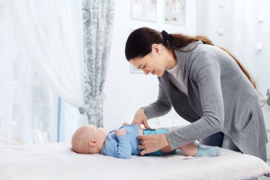 Annem tekrar kullanılabilir bir bezi, değişen bir masadaki bir bebekle değiştiriyor.