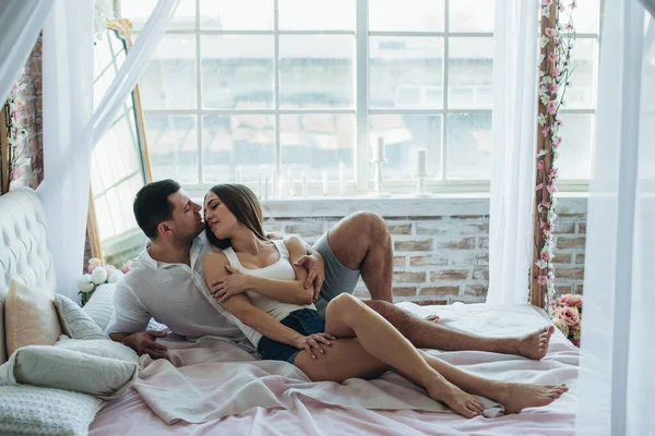 ベッドの上の寝室の若い恋人の男性と女性 ハグキスして — ストック写真