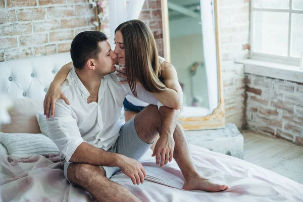 ベッドの上の寝室の若い恋人の男性と女性 ハグキスして — ストック写真