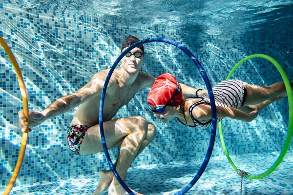 男性コーチとともに女の子でプールで泳ぐことを教えています水の下でリング — ストック写真
