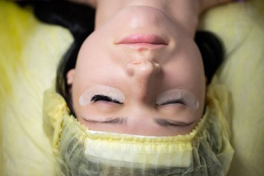 Efendi müşteriye büyük renkli kirpikleri biriktirir. Güzellik fotoğrafçılığına hazırlık. Bir resim oluşturuluyor.