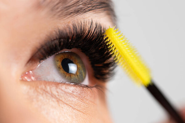 Portrait of a beautiful woman with eyelashes and eyebrow correction. Eye close up. Combing special brush