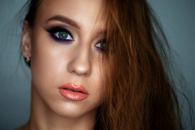 Karanlık bir arka planda güzel bir akşam makyajı olan genç bir kadının portresi.