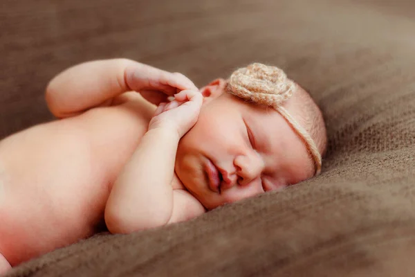 新生児の女の子の頭の上に花で茶色の背景 — ストック写真